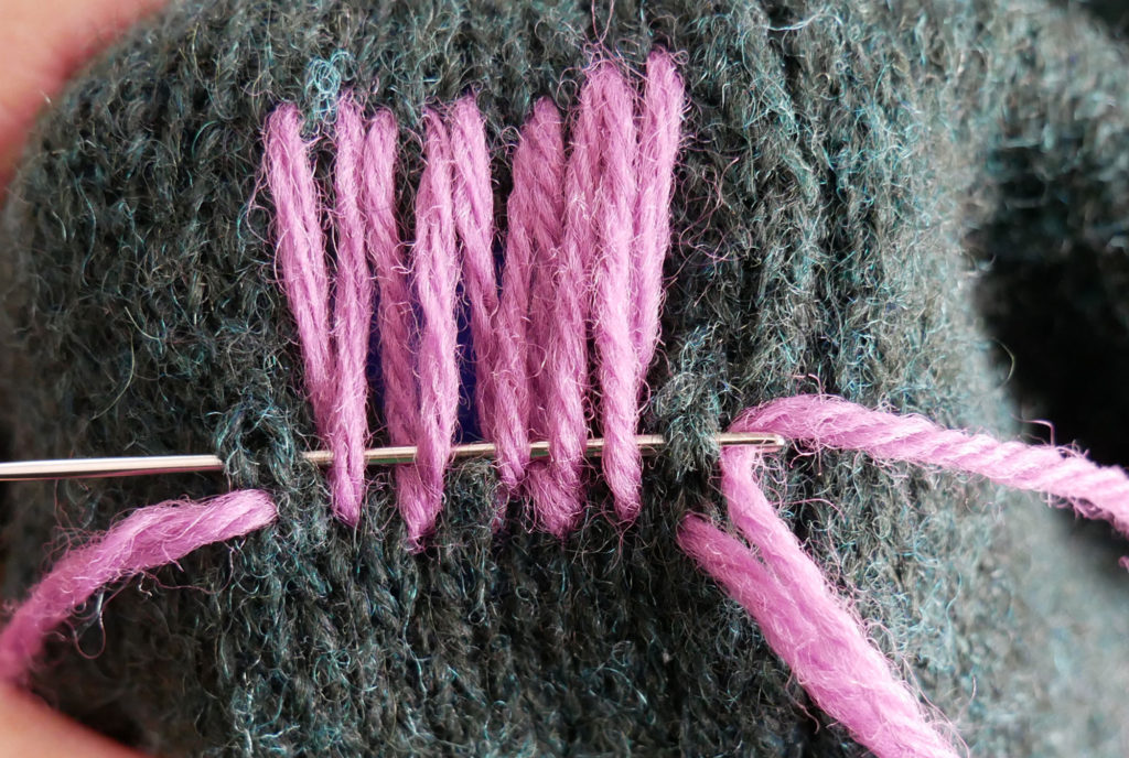Visible mending on a knitted jumper